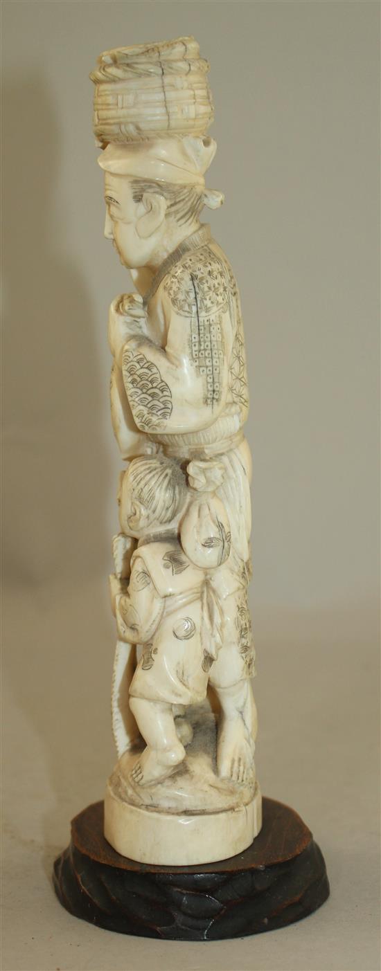 A Japanese walrus ivory group of a fisherman and a boy, early 20th century 21.5cm, wood stand